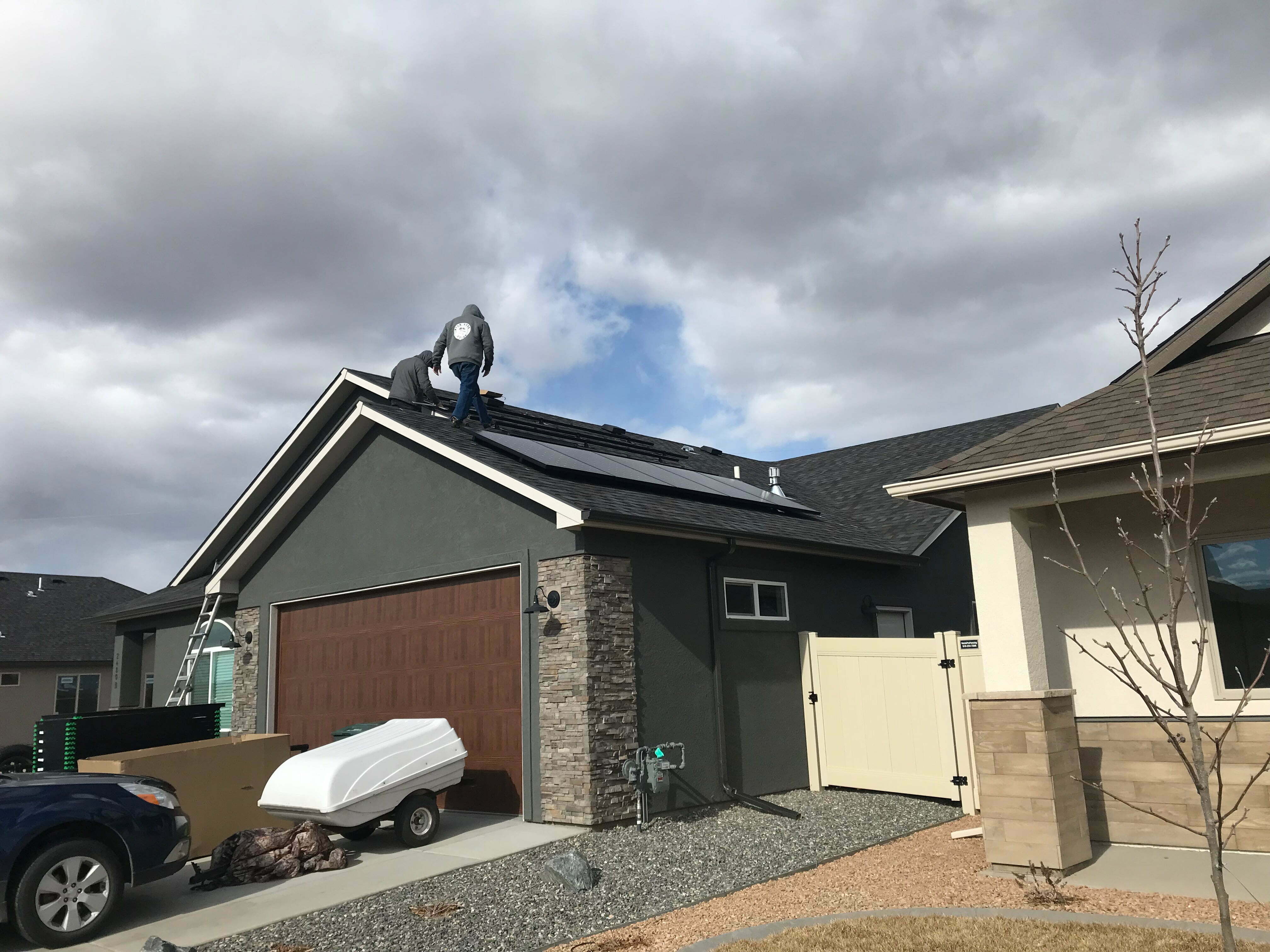 Installers placing black solar panels on a suburban garage roof